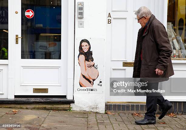 Member of the public walks past a stencilled spray painted piece of street art by street artist Pegasus titled Game of Thrones depicting a pregnant...