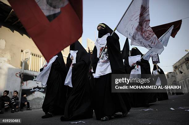 Bahraini Shiite Muslims women hold flag and portraits of a detained political activists in the village of Sanabis, west of Manama, on December 24 as...