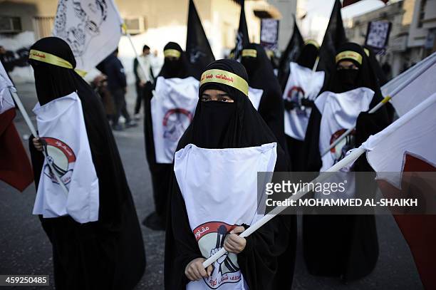 Bahraini Shiite Muslims women hold flag and portraits of a detained political activists in the village of Sanabis, west of Manama, on December 24 as...