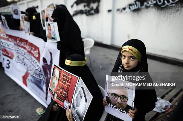 Bahraini Shiite Muslims women and girls hold flag and portraits of a detained political activists in the village of Sanabis, west of Manama, on...