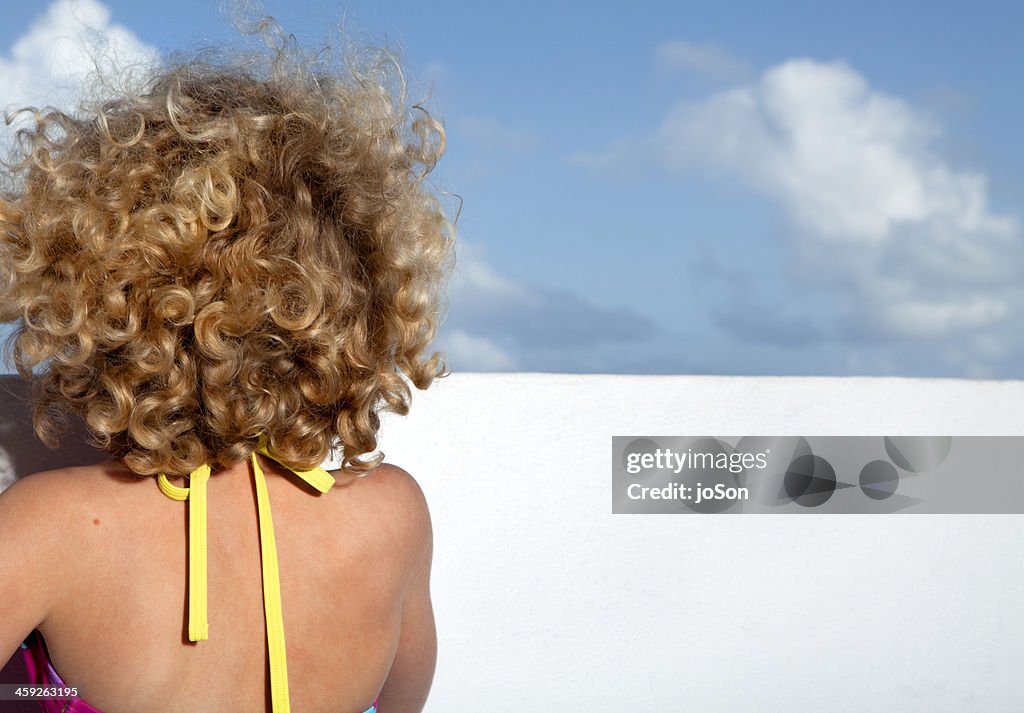 Back view of girl 4-8 on balcony, looking at beach