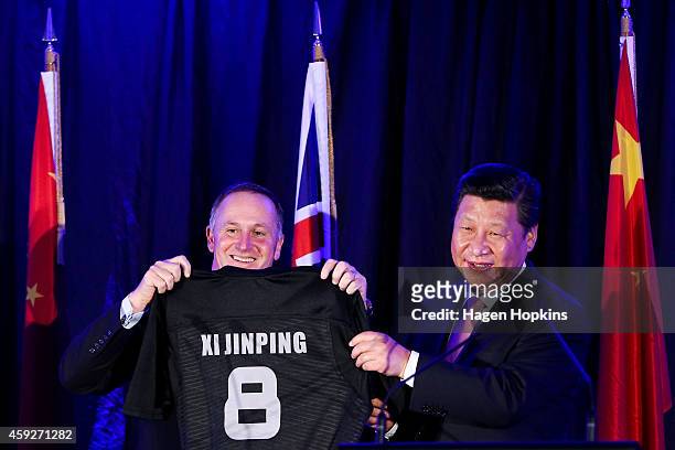 Prime Minister John Key of New Zealand presents President Xi Jinping of China with a personalised All Blacks rugby jersey during a signing of...