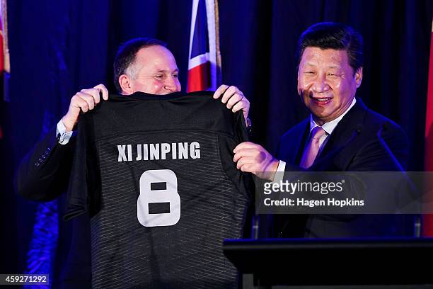 Prime Minister John Key of New Zealand presents President Xi Jinping of China with a personalised All Blacks rugby jersey during a signing of...