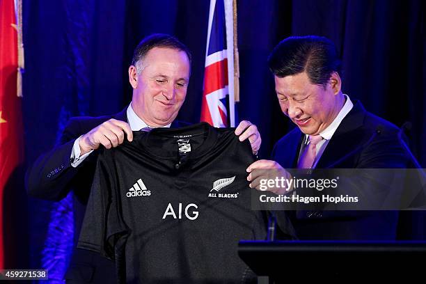 Prime Minister John Key of New Zealand presents President Xi Jinping of China with a personalised All Blacks rugby jersey during a signing of...