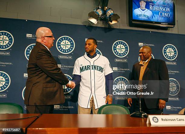 Jack Zduriencik of the Seattle Mariners shakes hands with Robinson Cano as manager Lloyd McClendon looks on during Cano's introductory press...