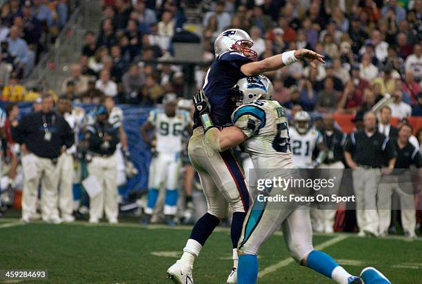 Tom Brady of the New England Patriots gets his pass off while getting hit by Dan Morgan of the Carolina Panthers during Super Bowl XXXVIII at Reliant...