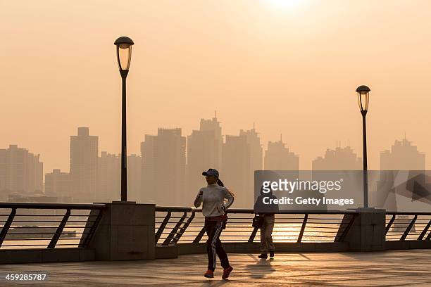 Girl runs at The Bund as heavy smog engulfs the city on December 25, 2013 in Shanghai, China. Heavy smog covered many parts of China on Christmas...