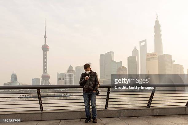 Man wearing mask stands at The Bund as heavy smog engulfs the city on December 25, 2013 in Shanghai, China. Heavy smog covered many parts of China on...