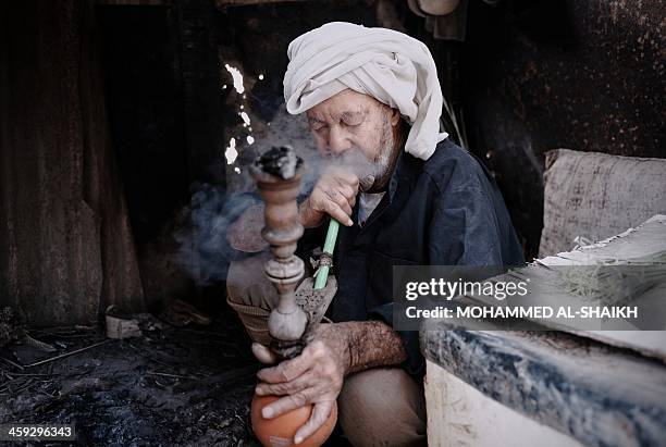 Bahrain farmer sits smoking a water pipe during a break as he works in his farm in the village of Bori, south of Manama, on December 25, 2013. AFP...