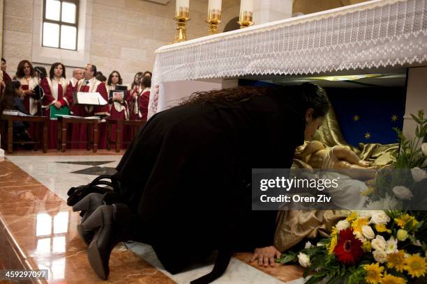 Christian worshipper kisses a Baby Jesus statue at the altar during the Christmas mass at the Church of the Nativity on December 25, 2013 in...