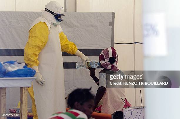 Nurse wearing a personal protective equipment assists a patient at the Ebola treatment center run by the French Red Cross society in Macenta in...