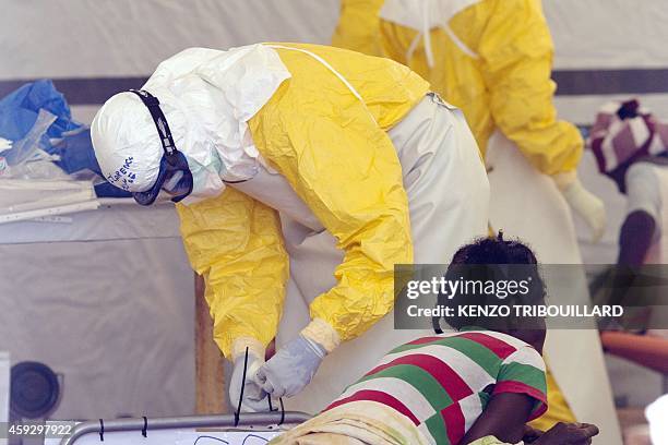 Nurse wearing a personal protective equipment assists a patient at the Ebola treatment center run by the French Red Cross society in Macenta in...