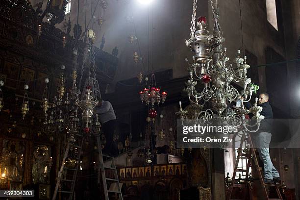 Workers clean the lights at the Church of the Nativity on December 25, 2013 in Bethlehem, West Bank. Every Christmas pilgrims travel to the church...