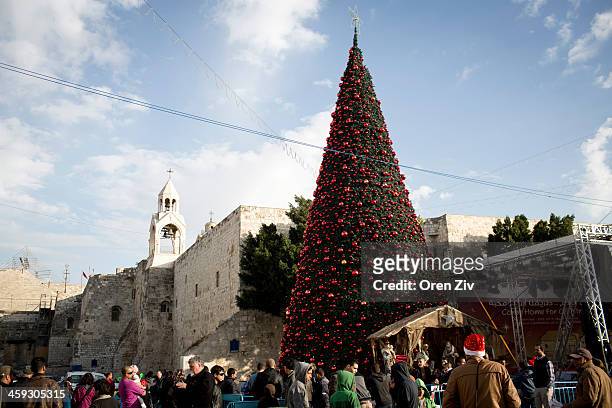 People walk past a Christmas tree outside the Church of the Nativity, traditionally believed to be the birthplace of Jesus Christ, on December 25,...