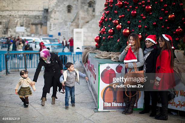 People pose for a photo next to a Christmas tree outside the Church of the Nativity, traditionally believed to be the birthplace of Jesus Christ, on...