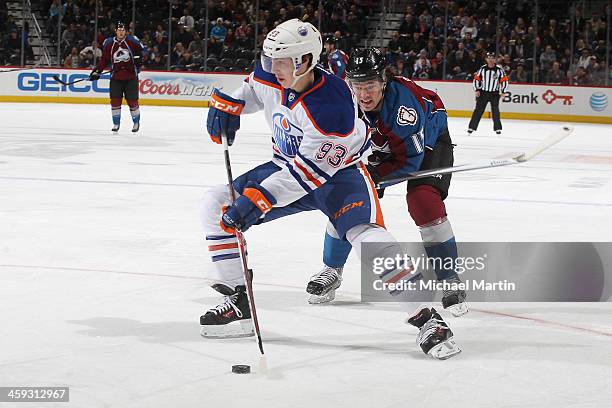 Ryan Nugent-Hopkins of the Edmonton Oilers handles the puck as PA Parenteau of the Colorado Avalanche closes in at the Pepsi Center on December 19,...