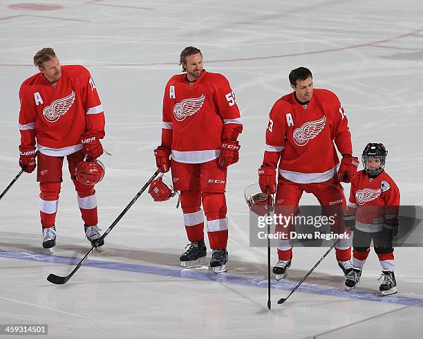 Daniel Alfredsson, Niklas Kronwall and Pavel Datsyuk of the Detroit Red Wings look over at the youth skater of the game Marko Ristic before an NHL...