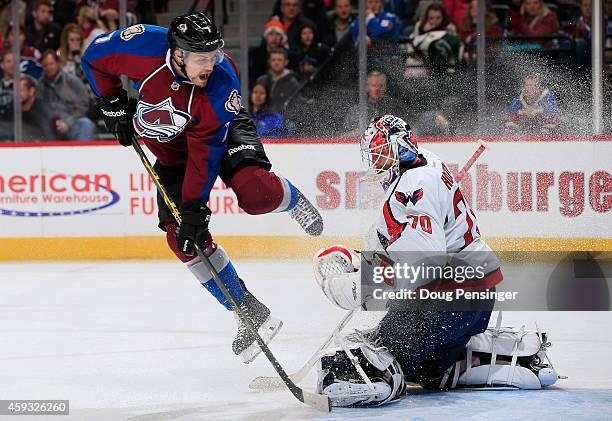 John Mitchell of the Colorado Avalanche leaps to avoid a shot by his teammate as goalie Braden Holtby of the Washington Capitals defends the goal at...