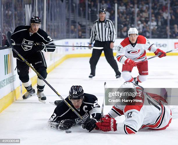 Dustin Brown of the Los Angeles Kings and Eric Staal of the Carolina Hurricanes fall near the puck as Brayden McNabb of the Los Angeles Kings and...