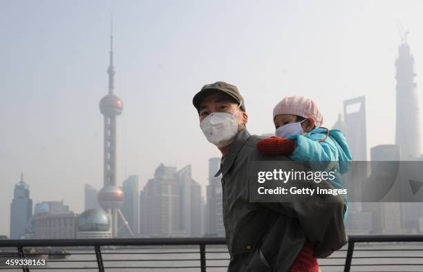 Man and his child wear masks as they visit The Bund on December 25, 2013 in Shanghai, China. Heavy smog covered many parts of China on Christmas Eve,...