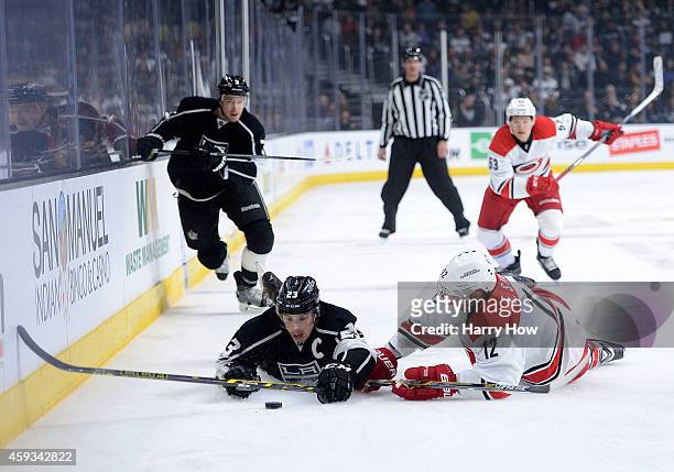Dustin Brown of the Los Angeles Kings and Eric Staal of the Carolina Hurricanes fall near the puck as Brayden McNabb of the Los Angeles Kings and...