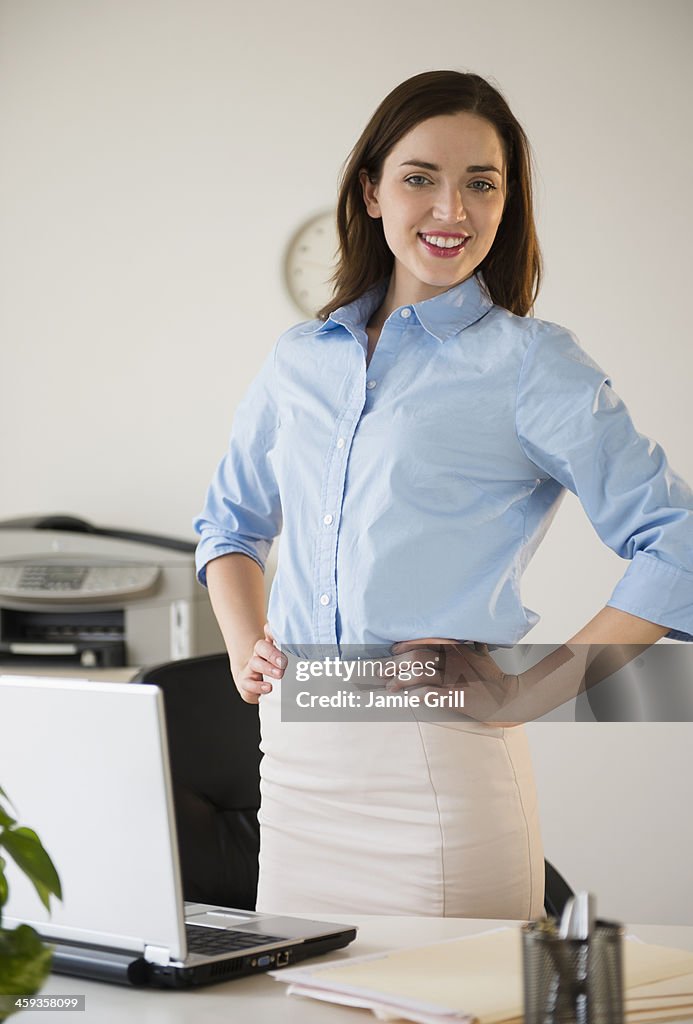 Businesswoman standing at desk, smiling