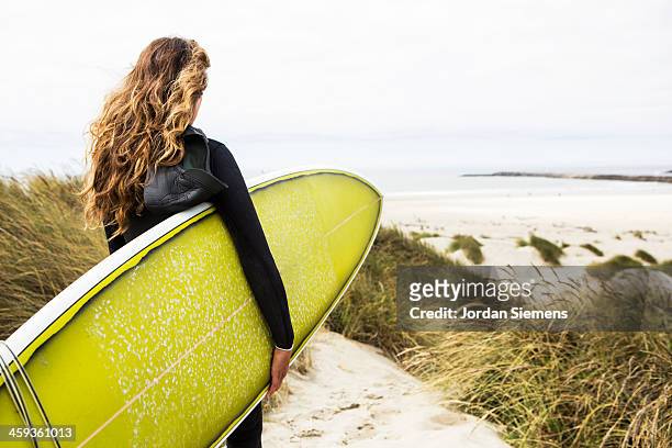 woman surfing in a wetsuit. - wavy hair beach stock pictures, royalty-free photos & images