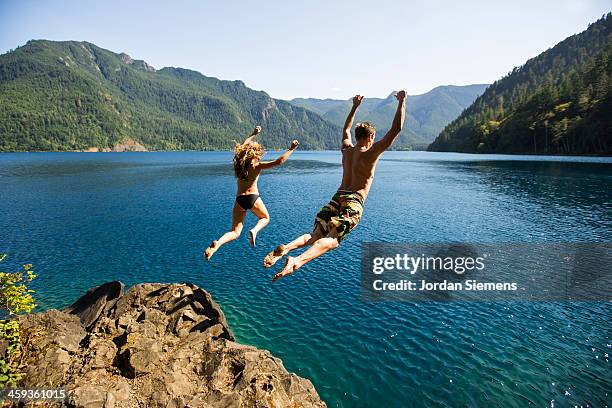 man and woman cliff jumping - salto desde acantilado fotografías e imágenes de stock