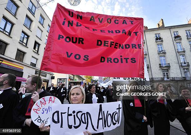 French lawyers dressed in their robes hold a banner reading "An independent lawyer to protect your rights" as they gather in front of the 'Maison de...