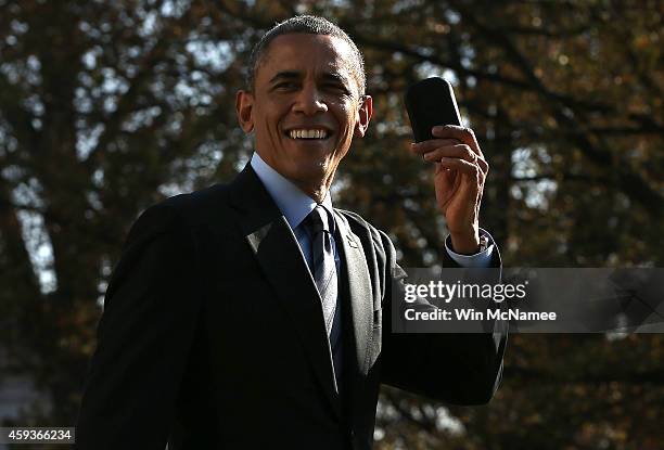 President Barack Obama holds up his Blackberry after he ran back into the White House after forgetting the mobile phone while departing for a...
