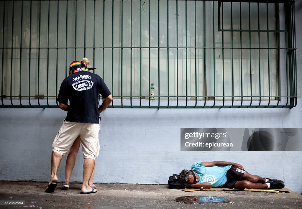 Homeless man sleeping while drunk couple makes out above him