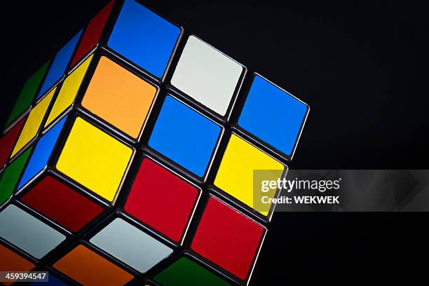 klassische rubik's cube auf schwarzem hintergrund - zauberwürfel stock-fotos und bilder