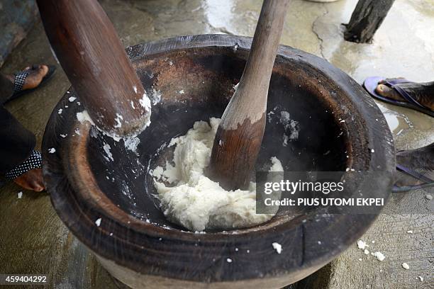 People pound boiled yams with a morter and pestle for as they prepare a pounded yam meal in Lagos on October 28, 2014. One of Nigeria's most popular...