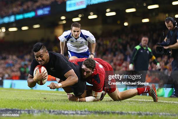 Julian Savea of the All Blacks scores his sides opening try despite the challenge from Alex Cuthbert of Wales during the International match between...