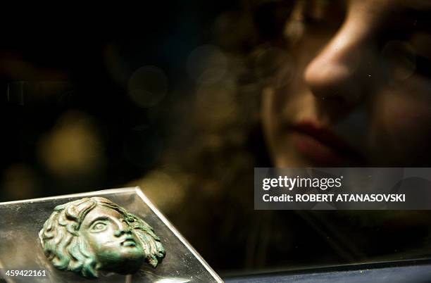 Woman looks at a third century bronze plated head of the Greek mythological figure Medusa presented during the annual archaeological exhibition at...