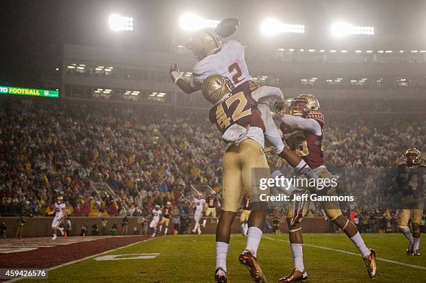 Lamarcus Brutus and P.J. Williams of the Florida State Seminoles defend against a trick play with Quaterback Tyler Murphy of the Boston College...