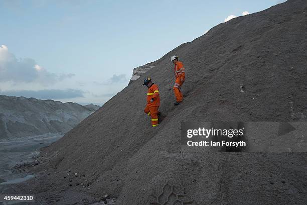 Two workers walk down after inspecting a pile of salt product at the potash facility at Tees Docks on November 20, 2014 in Tees Docks, United...