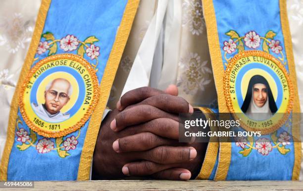 An Indian priest prays prior to a canonization mass for Indian priest Kuriakose Elias Chavara, represented at left, and Indian Carmelite nun...