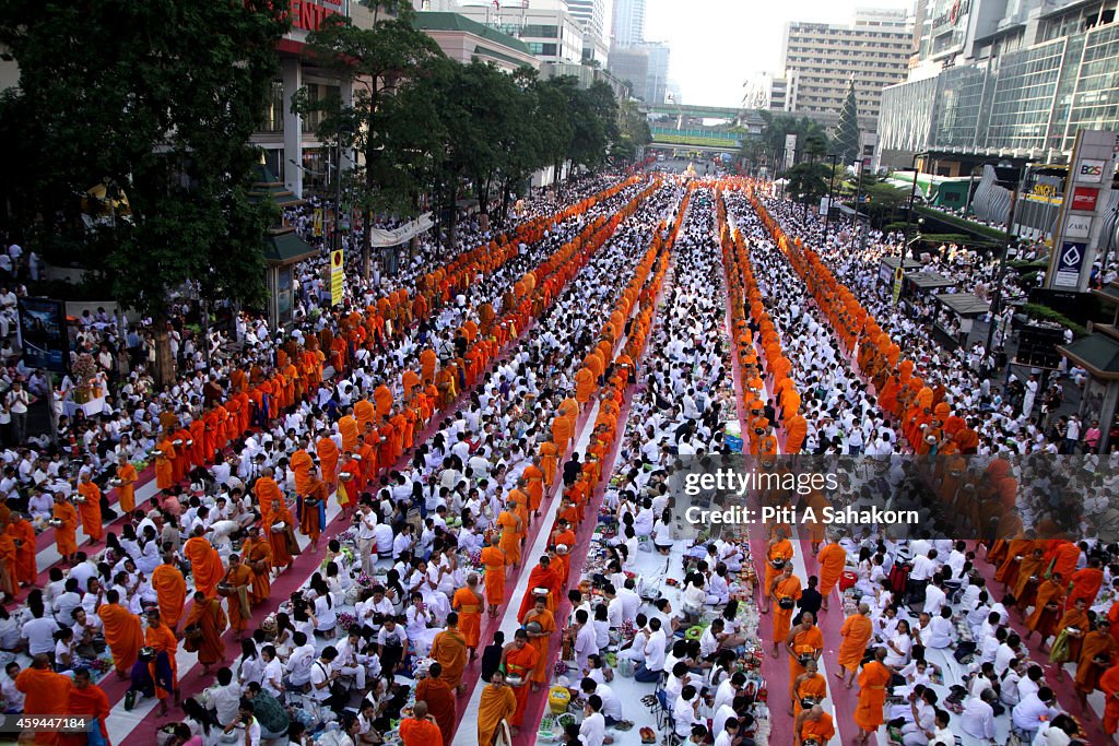 People drop dried food into bowls of Buddhist monks during a...