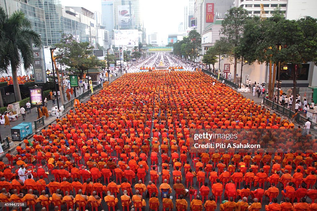 Buddhist monks carrying bowls before civilians drop dried...