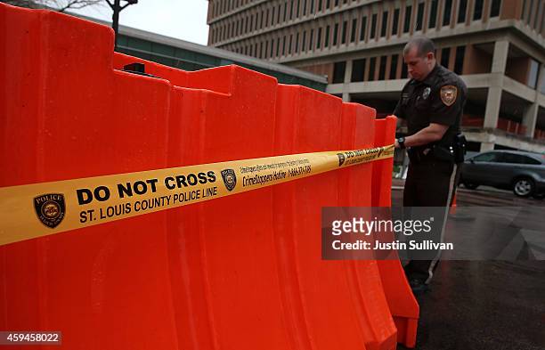 Security guard puts up police tape outside of the Buzz Westfall Justice Center where a St. Louis County grand jury is considering whether or not to...