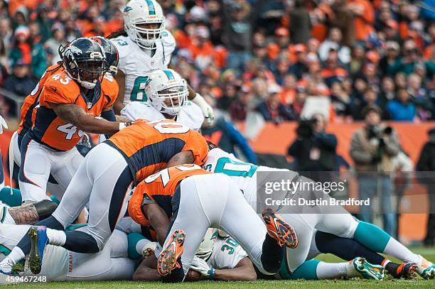 Running back Daniel Thomas of the Miami Dolphins is buried by defensive players after scoring a 3-yard rushing touchdown against the Denver Broncos...