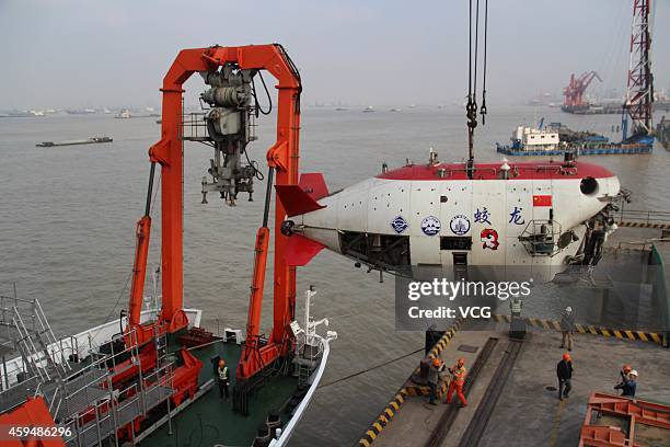 Workers install Jiaolong, China's manned deep-sea research submersible, onto its carrier Xiangyanghong 09 at Jiangyin Sunan International Container...