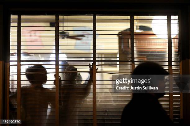 Restaurant patrons watch as demonstrators march through the streets while protesting the shooting death of 18-year-old Michael Brown on November 23,...