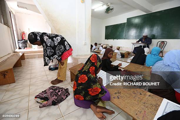 Muslim girl pray as other pupils read the Koran in a madrassa on March 26, 2013 in the city of Sada in the French overseas Indian Ocean archipelago...