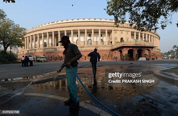 An Indian sweeper cleans the Parliament premises prior to the opening of the winter session in New Delhi on November 24, 2014. The Narendra Modi...