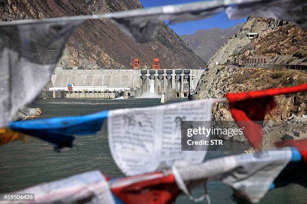 This picture taken on November 23, 2014 shows prayer flags hanging before the Zangmu Hydropower Station in Gyaca county in Lhoka, or Shannan...