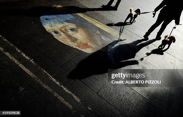 People walk on a street drawing depicting the "Girl with a Pearl Earring" by Vermeer on November 24 2014, in central Rome. AFP PHOTO / ALBERTO PIZZOLI