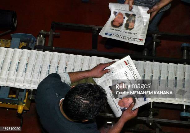 Print workers for the English-language Israeli daily newspaper Jerusalem Post inspect the first edition showing pictures of the captured Saddam...
