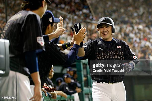 Seiichi Uchikawa of Samurai Japan is greeted in the dugout after scoring a run in the second inning against the MLB All-Stars during the game at...